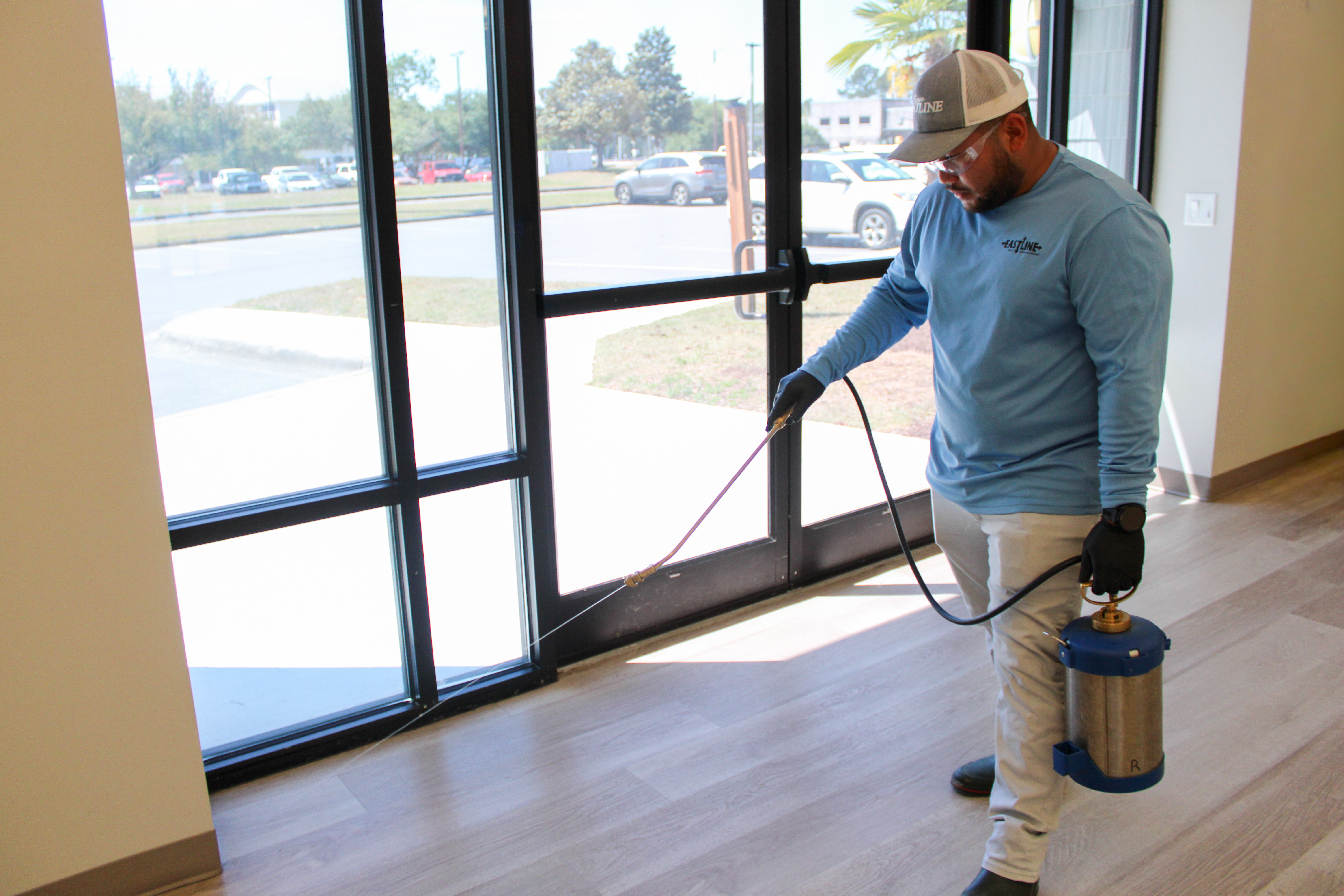 Eastline technician performing interior commercial pest control treatment along entry points in New Bern NC